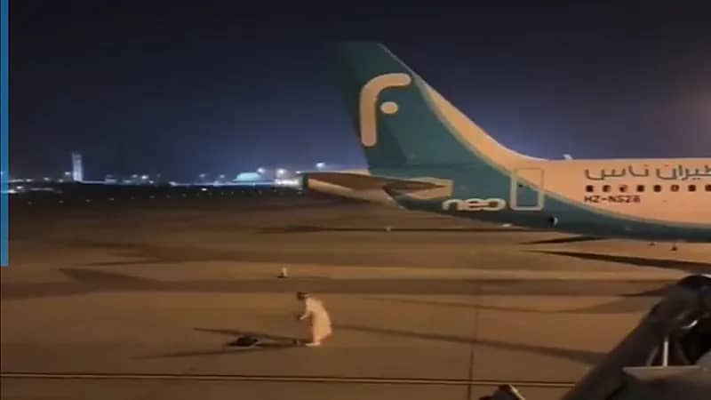 شخص يصلي في مدرج الطائرات وموظفة تقاطعه .. فيديو