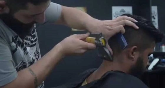 بالفيديو.. سوري يحلق لزبائنه بالمطرقة والبلطة يثير دهشة المتابعين